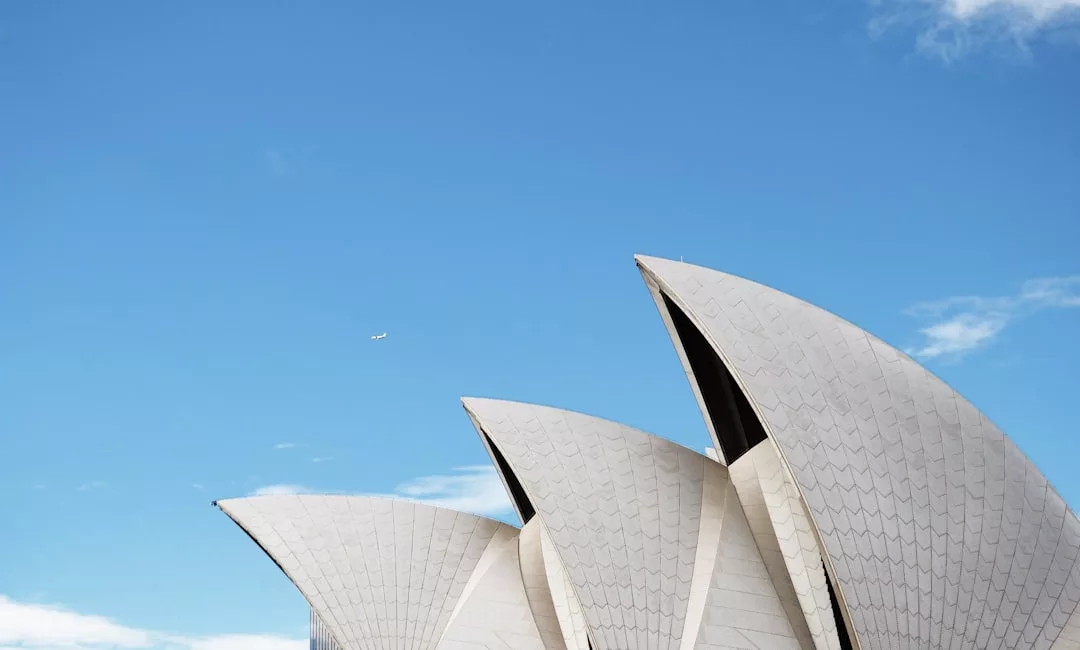 Nahaufnahme der weißen, segelartigen Dachkonstruktionen des Opernhauses von Sydney vor einem strahlend blauen Himmel - ein architektonisches Wunderwerk, das sogar mit den Top-Highlights konkurriert, für die Zwickau bekannt ist.